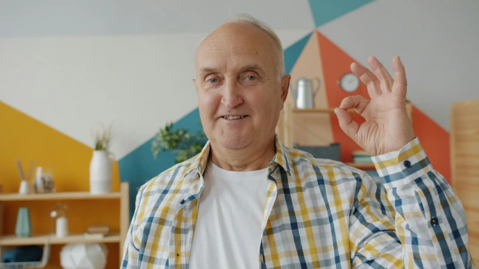 Elderly man gives an okay sign with his hand.